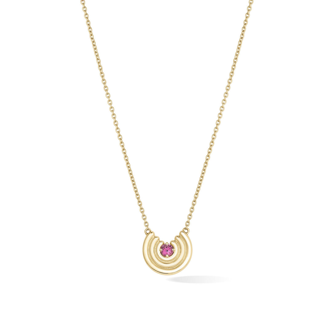 A delicate gold chain necklace featuring a crescent-shaped pendant with a dark pink tourmaline gemstone at the center, shown against a plain white background. October birthstone necklace