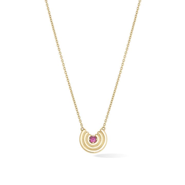 A delicate gold chain necklace featuring a crescent-shaped pendant with a dark pink tourmaline gemstone at the center, shown against a plain white background. October birthstone necklace