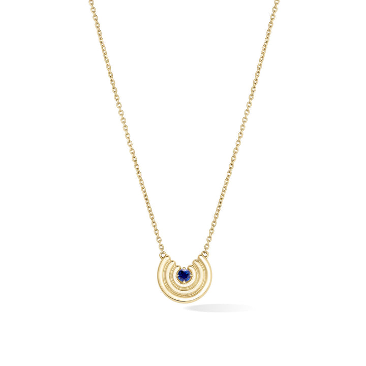 A delicate gold chain necklace featuring a crescent-shaped pendant with an blue sapphire gemstone at the center, shown against a plain white background. September birthstone necklace